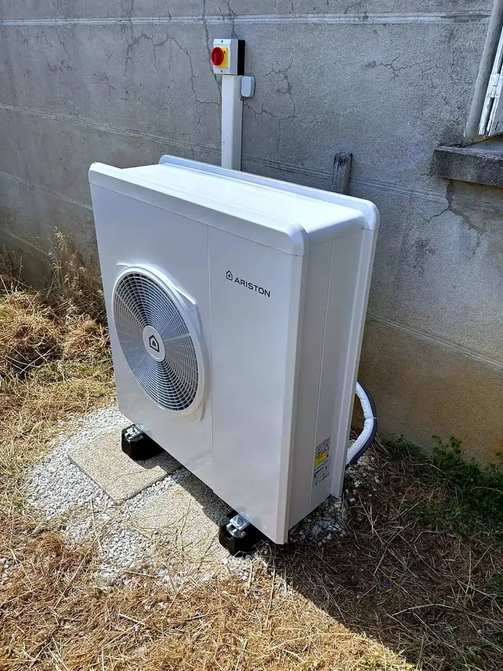 Unité extérieure de pompe à chaleur Ariston posée dans un jardin