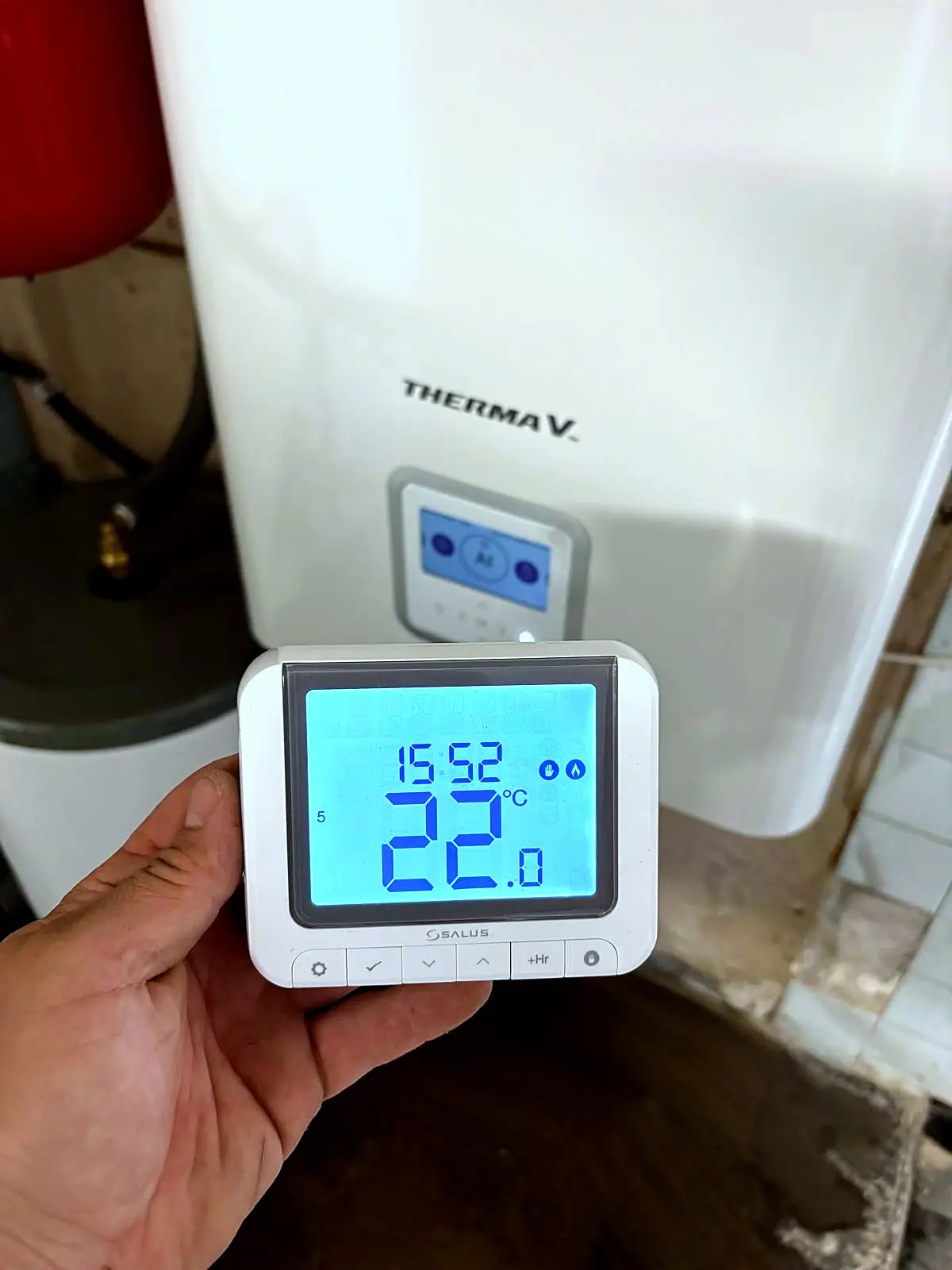 Main réglant un thermostat affichant 22 degrés